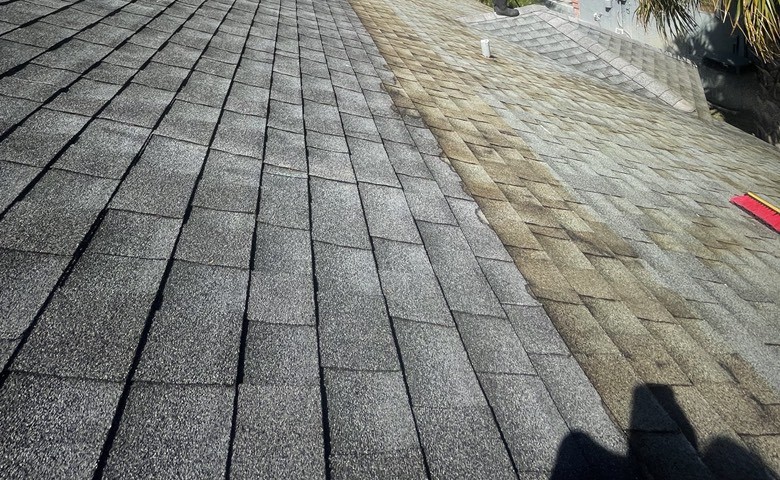 One roof mid-job: the left half still dark with algae, the right half under an ongoing chemical treatment